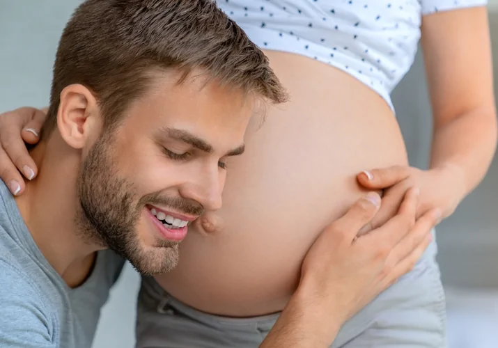 Těhotná žena s bříškem dotýká se jí její muž.
