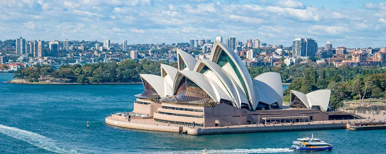 Fotografie ikonické budovy Opery v Sydney na pozadí města.
