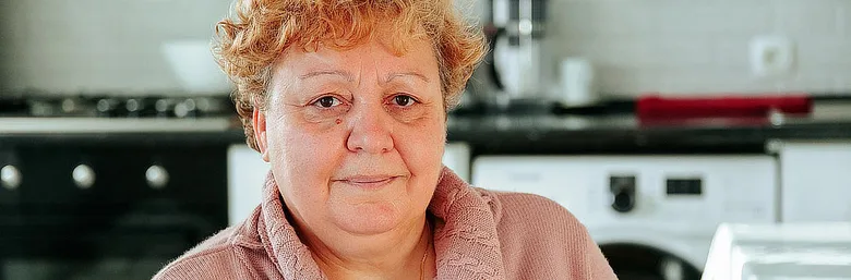 Žena v kuchyni se dívá na kameru.