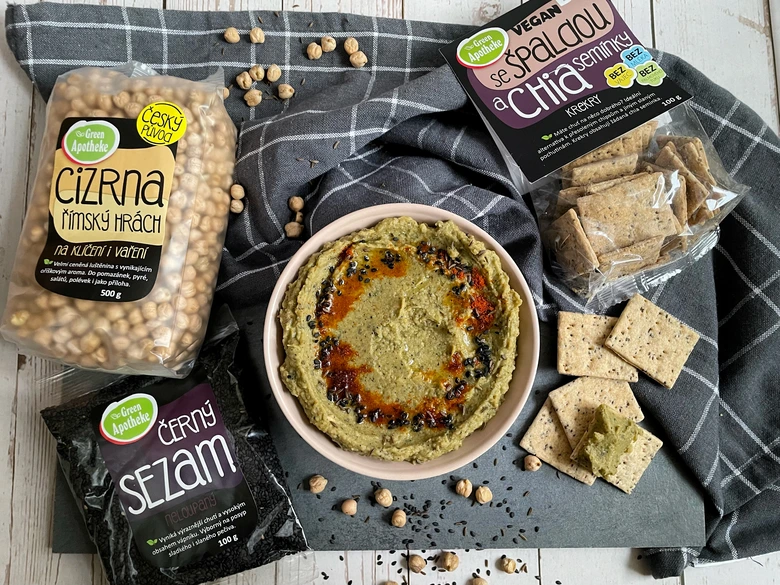 Zdravá vegan jídla s cizrny, sezamem a sušenkami na tmavém podkladu.
