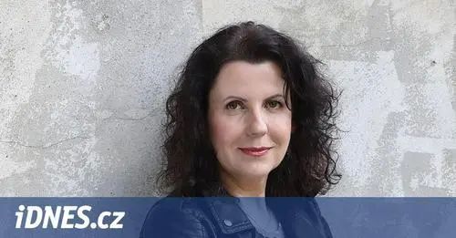 Portrét ženy s tmavými vlasy na texturované zdi.