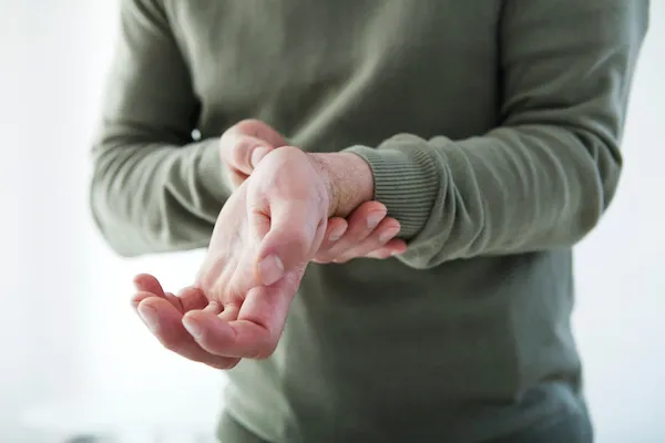 Muž masíruje zápěstí kvůli zánětu šlach.