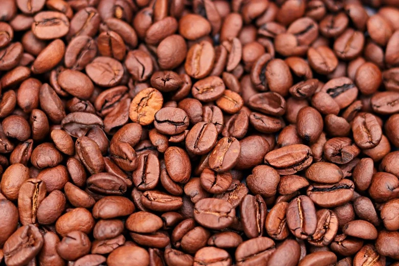 Detailní fotografie pražených kávových zrn na celém snímku.