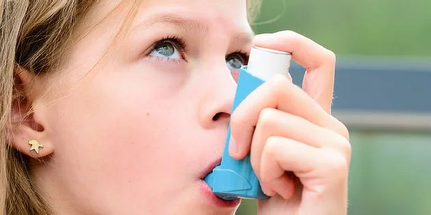Dívka používá inhalátor pro léčbu dýchacích cest.
