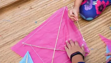 Ruční stavba draka z papíru s dřevěnými tyčkami na bambusové podlaze.