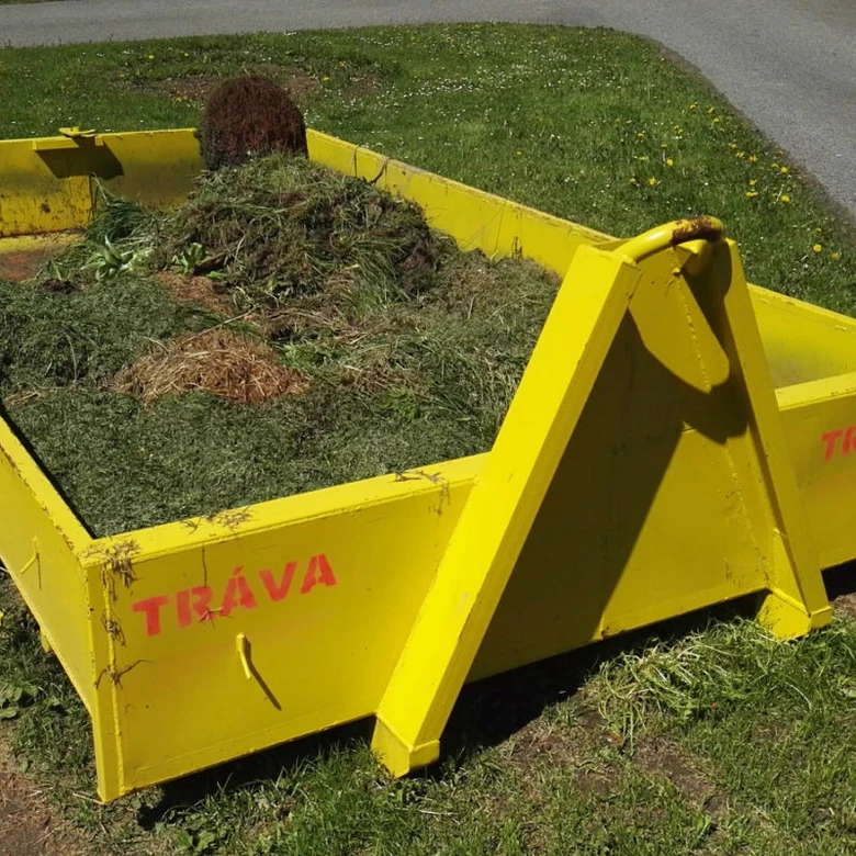 Žlutý kontejner na bioodpad s trávníkovými střihy venku.