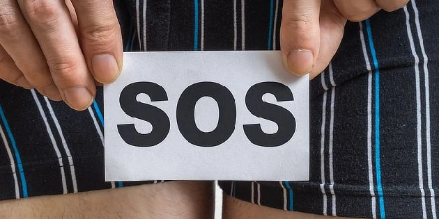 Ruce drží bílou kartu s nápisem SOS jako výzvu o pomoc.