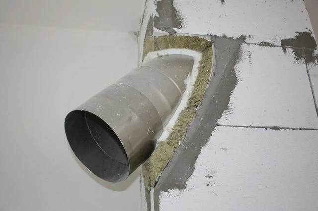 Instalace izolace do komína v zdi s použitím skelné vaty.