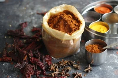 Různé koření s suchými chilli papričkami na šedém povrchu.