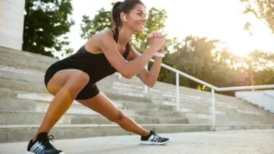 Žena v sportovním oblečení dělá cvičení na venkovních schodech.