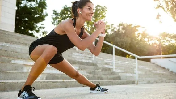 Žena v sportovním oblečení dělá cvičení na venkovních schodech.
